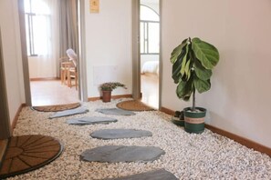 Un sendero con piedras para pisar que lleva a una habitación con una cama y un ventanal.