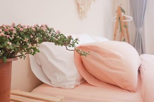 Un dormitorio acogedor con una cama, una planta en maceta y un colgador de macramé en la pared.