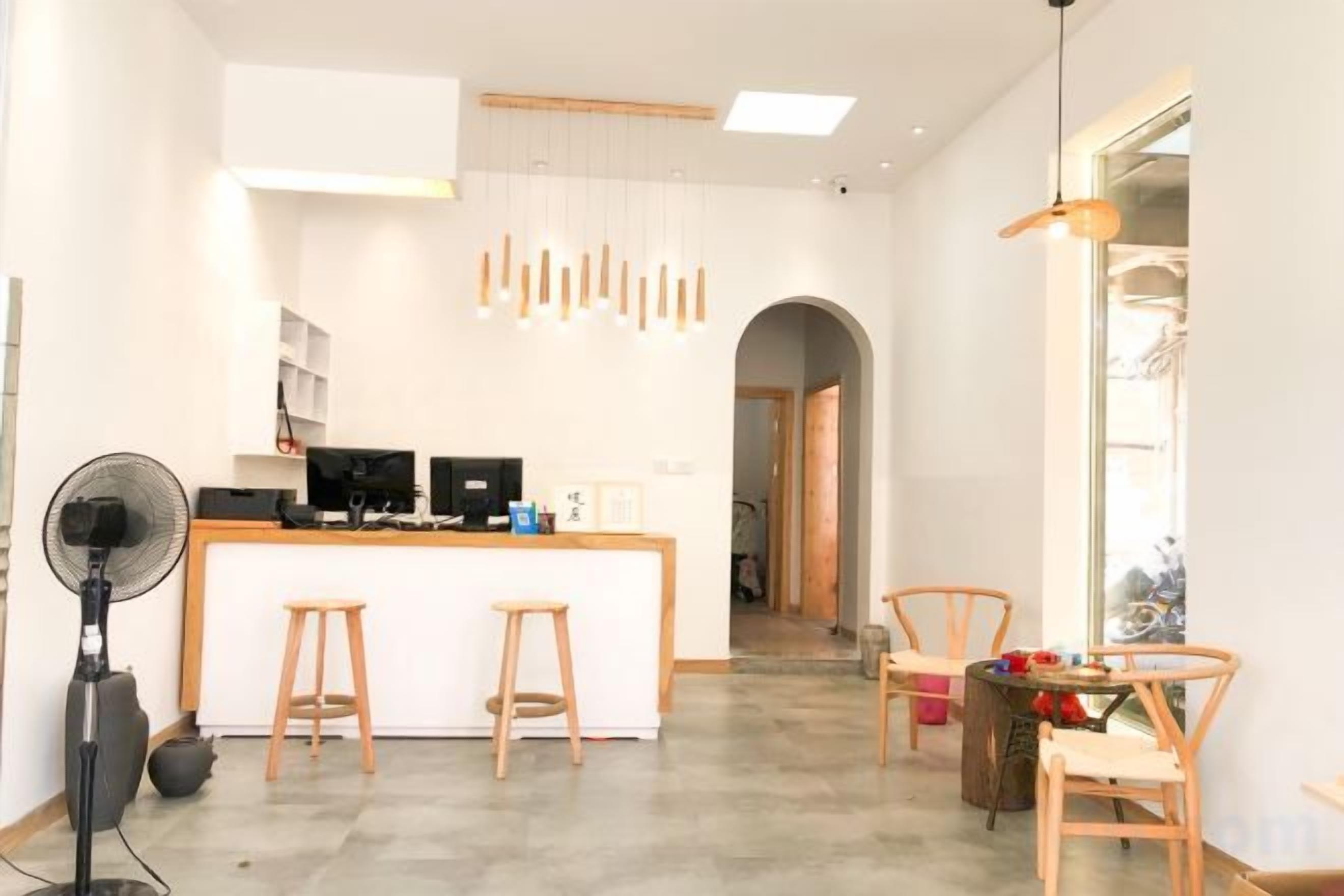 A modern kitchen with a central island, bar stools, and a fan.