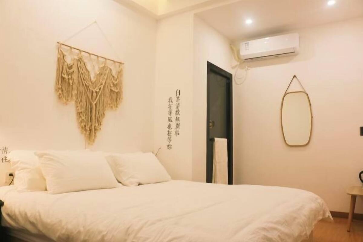 A bedroom with a bed, a wall-mounted air conditioner, and a door.