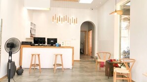 A modern kitchen with a central island, bar stools, and a fan.