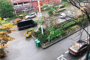 Escena callejera con vehículos, una bicicleta y un bote de basura verde.