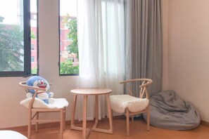 A room with a window, a plush toy, two chairs, a small table, and a bean bag. - Qianzihu Boutique Guesthouse (Fuzhou)