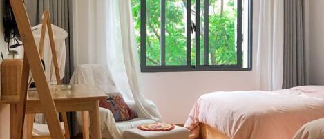 Un dormitorio con cama, una silla, un ventanal con vistas a zonas verdes y suelo de madera.