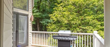 A covered porch with wicker furniture and a grill.