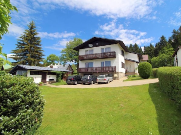 A two-story building with a balcony, a small attached garage, and a well-maintained lawn.