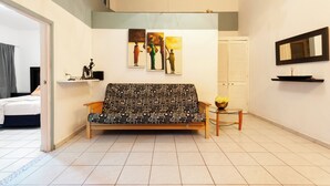 A modern living room with a patterned sofa, a small table with a vase, and wall art depicting people.