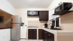 A compact kitchen with a refrigerator, stove, microwave, and cabinets.