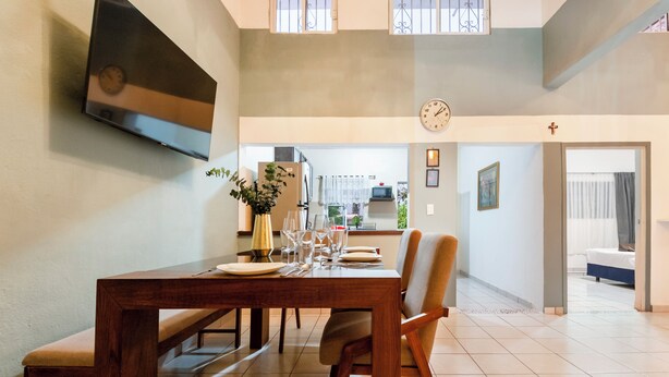 A dining area with a wooden table set for four, a bench, and a potted plant.