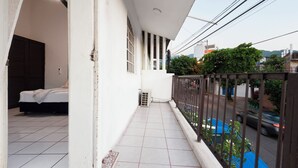 A balcony with a bed, a ceiling fan, and a view of the street.