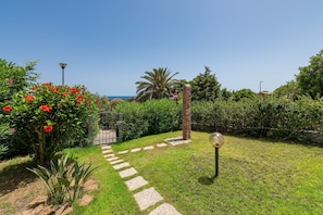 Un jardí amb un camí, una porta i un fanal.