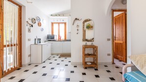 Une pièce avec un sol à carreaux, une porte en bois, un miroir et une petite table.