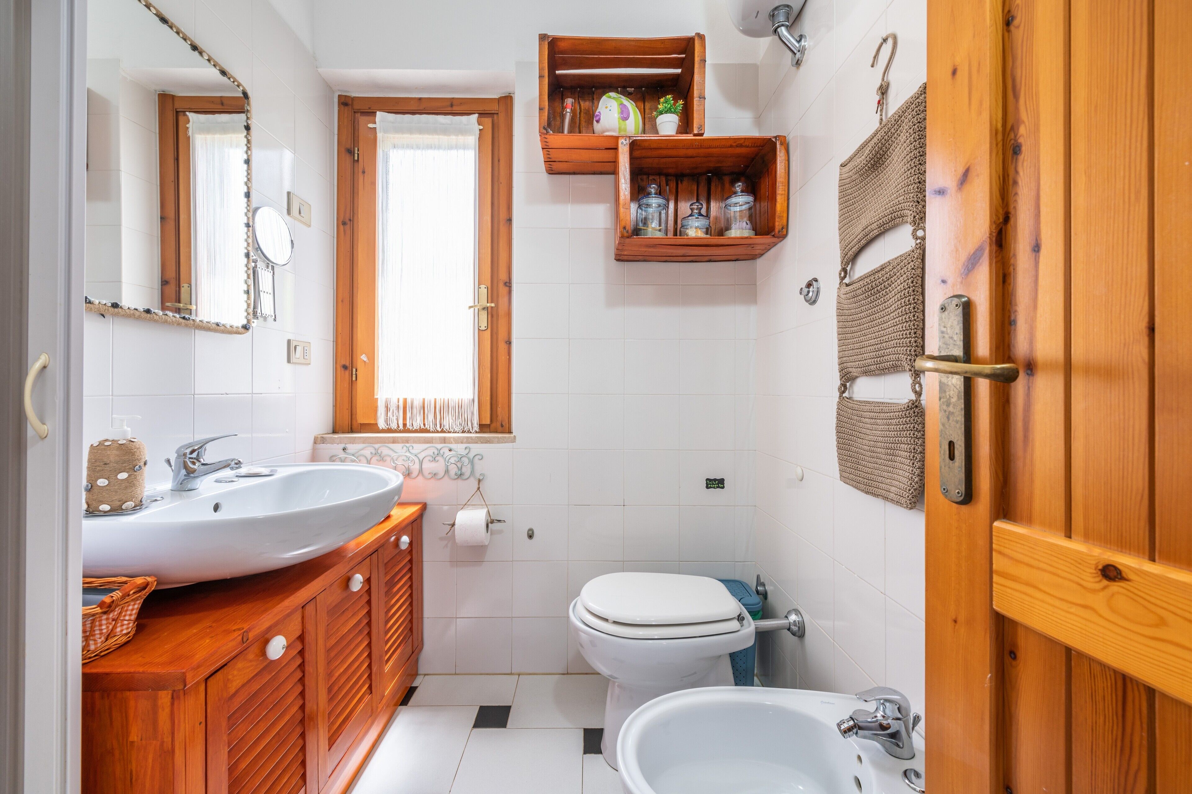 A bathroom with a wooden vanity, a sink, a toilet, and a bidet.