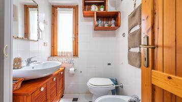 A bathroom with a wooden vanity, a sink, a toilet, and a bidet.