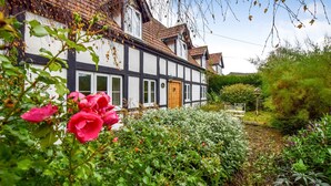 A traditional half-timbered house with a well-maintained garden, a wooden door, and a bench in the foreground. - Landers, Cheltenham - sleeps 10 guests  in 5 bedrooms (Cheltenham)
