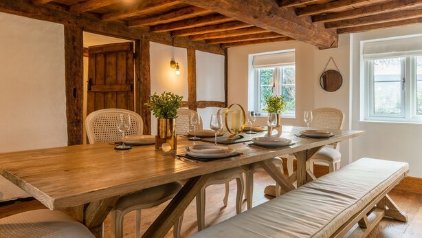 A wooden dining table set with plates, glasses, and a vase with greenery. - Landers, Cheltenham - sleeps 10 guests  in 5 bedrooms (Cheltenham)