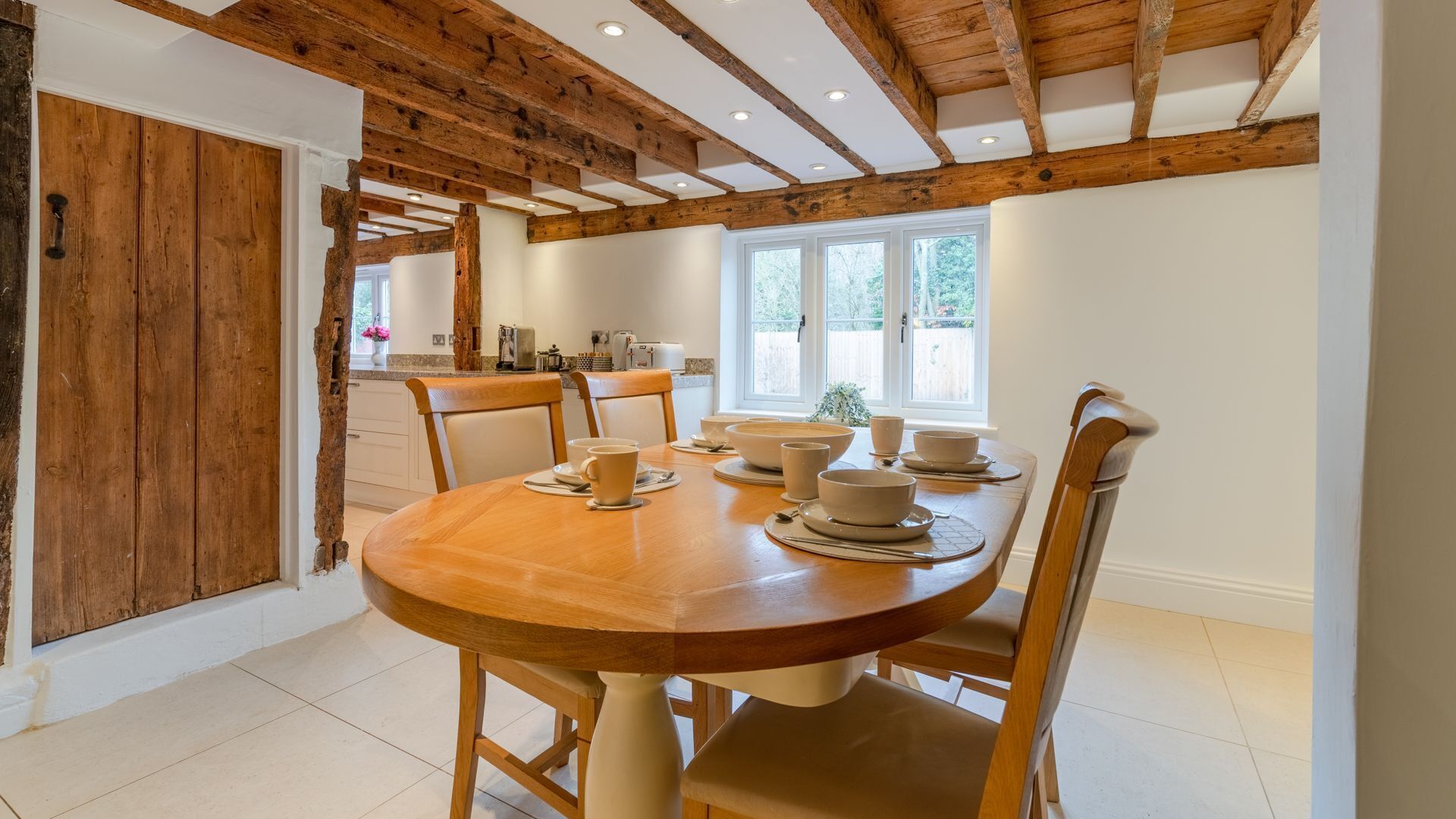 A dining area with a wooden table set for four, surrounded by chairs.