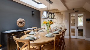 Un comedor con una mesa redonda de madera dispuesta para seis personas, rodeada de sillas de madera. En el fondo, se ve una pared de piedra y una puerta con la etiqueta "PRIVATE".