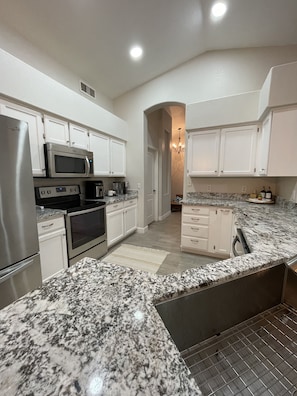 Enjoy cooking in this well-lit kitchen with oven, microwave, and refrigerator.