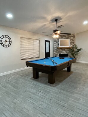 Enjoy a game of pool in this spacious room featuring a large pool table and a cozy fireplace.