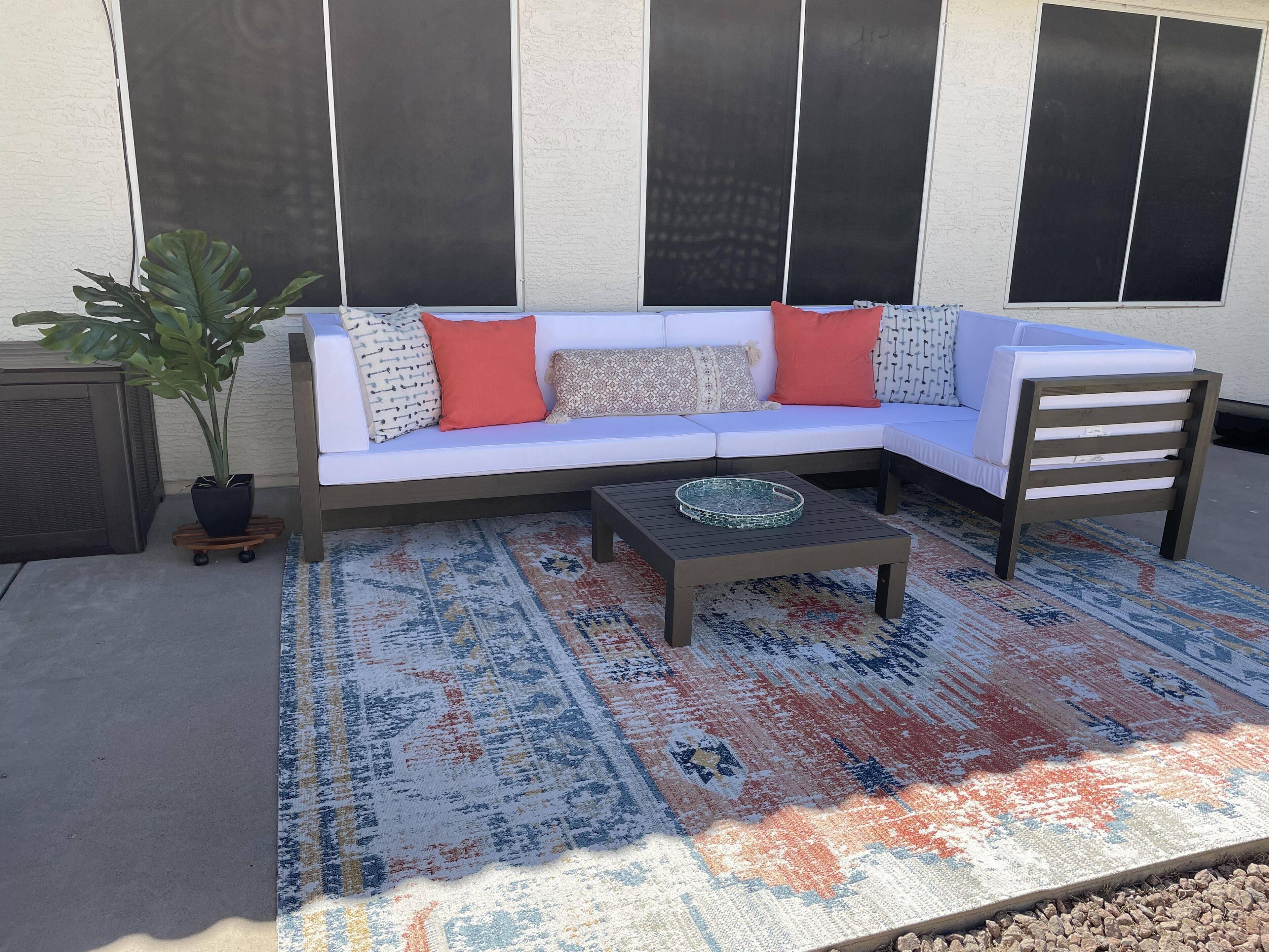 A sectional sofa with a tray table and a patterned rug.