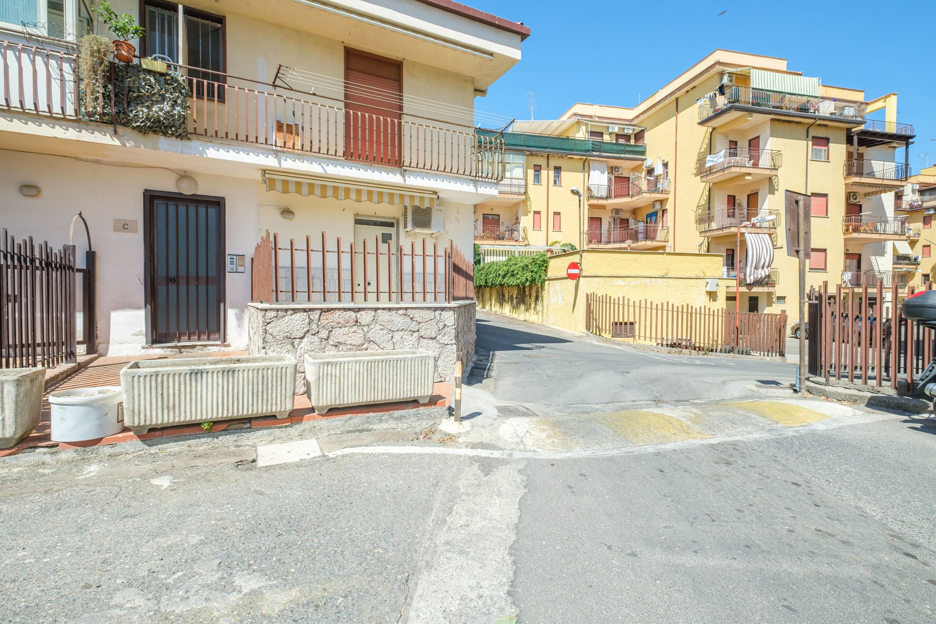 A residential street with multi-story buildings, balconies, and a clear sky.