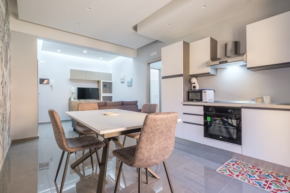 A modern kitchen with a dining area, a built-in oven, and a television.