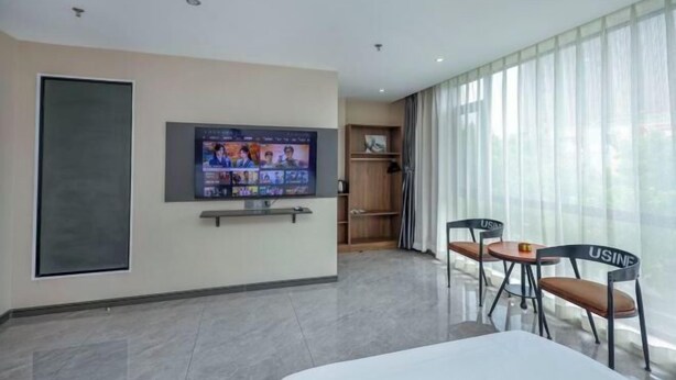 Habitació d'hotel amb televisió, llit, escriptori i cadira.