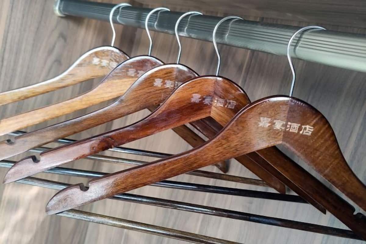 Cabides de madeira com texto, pendurados em uma estante de metal.