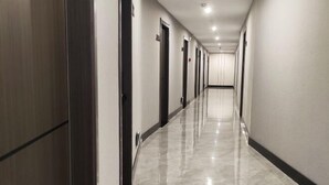 Passadís allargat i estret d'un hotel, amb un paviment brillant i reflectant i portes de fusta fosca a un costat.