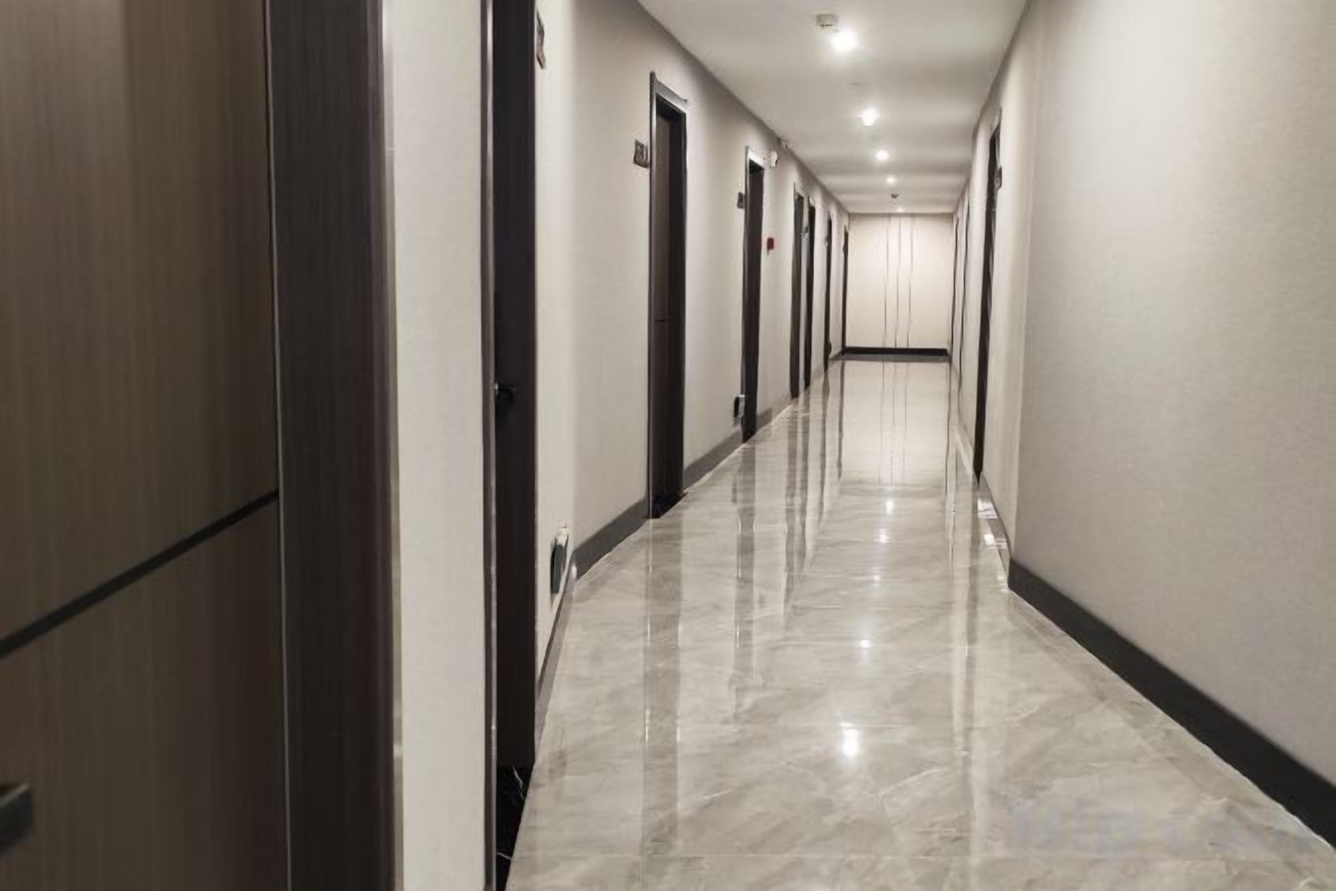A long, narrow hallway with doors on both sides, leading to individual rooms.