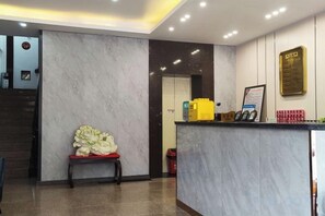 A reception area with a marble wall, a reception desk, a bench, and a framed sign. - Dalian Jiayan Collection Hotel (Dalian)