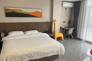 A hotel room with a bed, a desk, a giraffe statue, and a painting on the wall. - Dalian Jiayan Collection Hotel (Dalian)