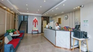 Rebedor d'hotel amb una taquilla, unes escales, un sofà i una decoració penjant.