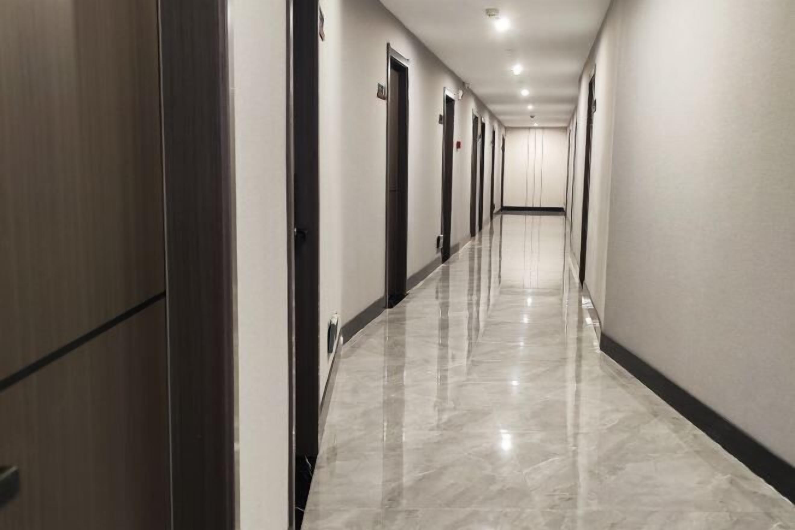 Un long couloir étroit, avec des portes d’un seul côté et un plancher ciré.