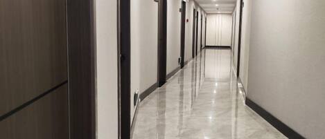 A long, narrow hallway with doors on one side and a polished floor.