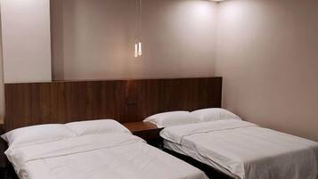 Habitación de hotel con dos camas individuales, un cabecero de madera y una lámpara colgante.
