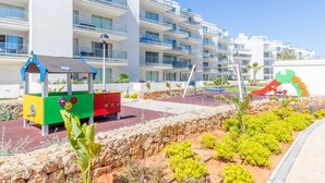 Un hôtel moderne doté de nombreux balcons, d’un espace de jeux pour enfants et de jardins aménagés.