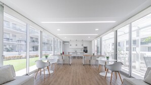 Une cuisine moderne avec des meubles blancs, un îlot central et une vue sur l’extérieur.