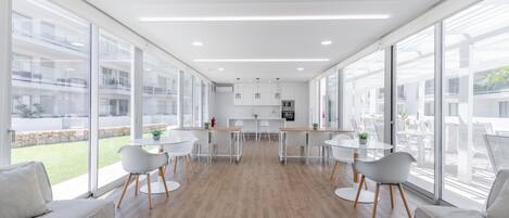 Una cocina moderna con armarios blancos, una isla central y vistas al exterior.