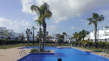 Piscina cercada por palmeiras e edifícios modernos.