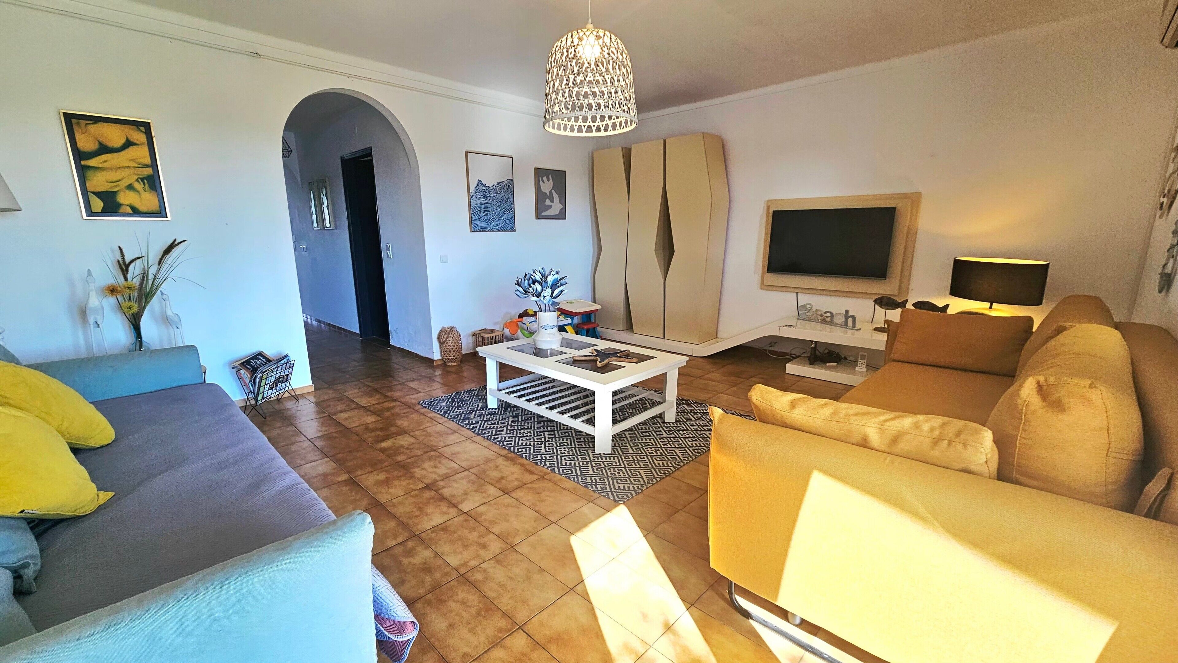 Olohuone, jossa on sohva, sohvapöytä, televisio ja lamppu.