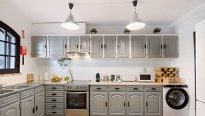 Une cuisine avec des meubles de couleur grise, une cuisinière, un four, un four à micro-ondes et un lave-linge.