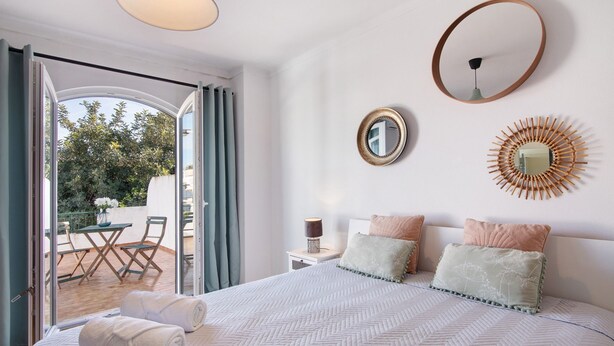 Une chambre à coucher comprenant un lit, deux tables de chevet, un miroir et un élément de décoration murale.