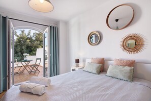 A bedroom with a bed, two bedside tables, a mirror, and a wall decoration.
