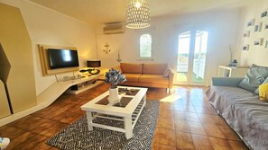 Un salon équipé d’un téléviseur à écran plat, d’un canapé, d’une table basse agrémentée d’objets décoratifs et d’un tapis à motifs.