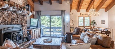 Una sala de estar acogedora con chimenea, sofás de cuero y un comedor con vistas al exterior.