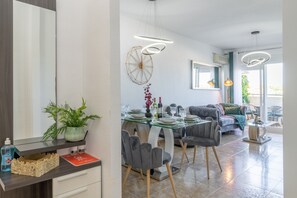 Un comedor moderno con una mesa de vidrio, sillas grises e iluminación colgante.