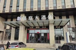 A hotel entrance with a covered walkway and a sign above the doors. - Zhoushan Xinxiting Grand Hotel (Zhoushan)