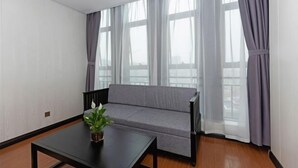 A room with a grey sofa, a black table with a plant, and large windows with curtains. - Zhoushan Xinxiting Grand Hotel (Zhoushan)